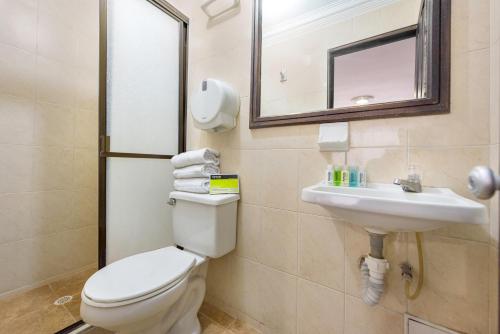 a bathroom with a toilet and a sink and a mirror at Ayenda 1120 Hotel Comercial in Pereira