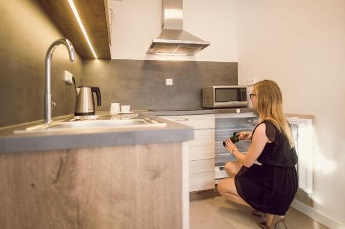 a woman sitting in a kitchen holding a bottle at Kings Residence in Prague