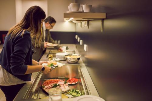 a man and woman preparing food in a restaurant kitchen at Kings Residence in Prague