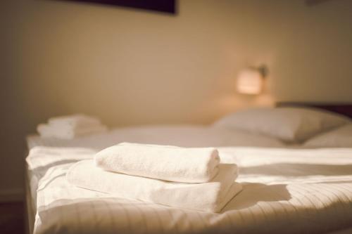 three white towels are stacked on a bed at Kings Residence in Prague