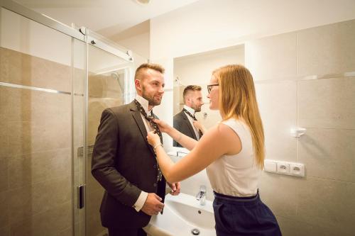 a woman adjusting a mans tie in front of a bathroom mirror at Kings Residence in Prague