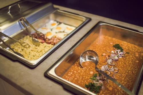 a buffet with two trays of food and a spoon at Kings Residence in Prague