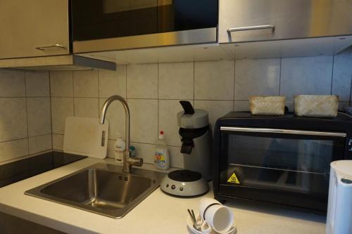 a kitchen counter with a sink and a microwave at B&B Bosrand in Groesbeek