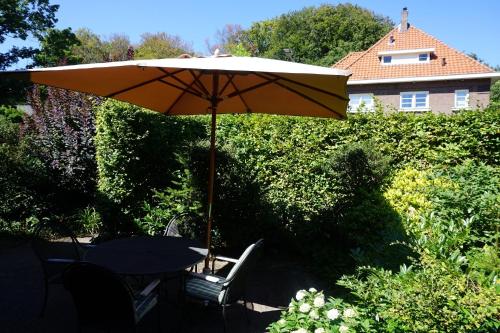 a table and chairs under an umbrella in a yard at B&B Bosrand in Groesbeek
