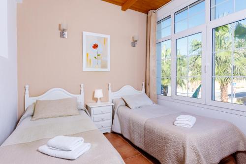 two beds in a room with a window at AT Almoraide Rooms Suites in Nerja