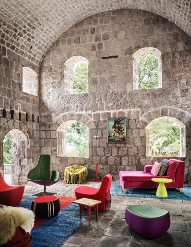 a living room with colorful furniture and a brick wall at Golden Rock Nevis in Nevis