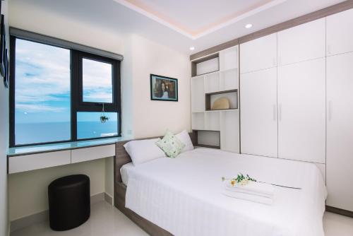 a bedroom with a white bed and a window at Da Nang Daisy Apartment in Da Nang