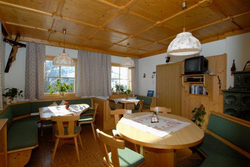 a restaurant with tables and chairs and a tv at Haarlehenhof in Grossarl