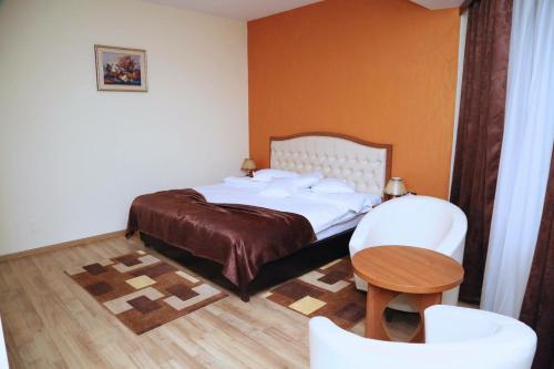 a bedroom with a bed and a table and chairs at Hotel Crystal Palace in Râmnicu Vâlcea