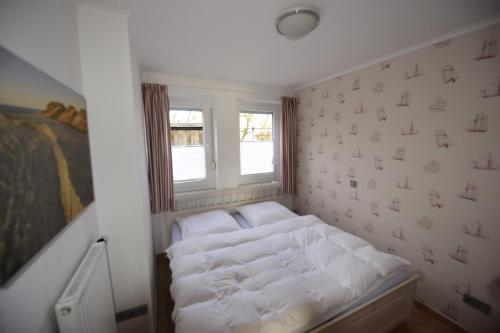 een kleine slaapkamer met een wit bed en een raam bij Großzügige Familienwohnung - mit grossen Esszimmer in Juist