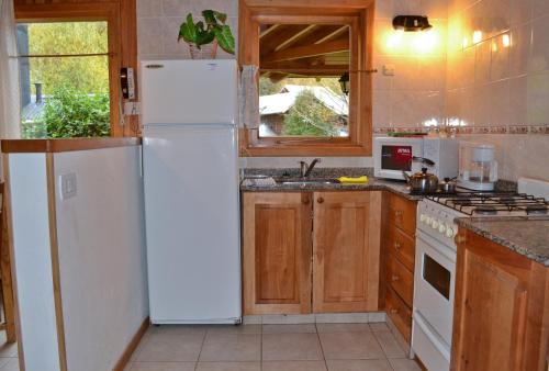 a kitchen with a white refrigerator and wooden cabinets at Apart Hotel del Pellin in San Martín de los Andes