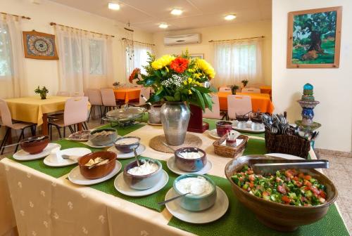 Kibbutz Inbar Country Lodging في Kibbutz Inbar: طاولة مع أطباق من الطعام و إناء من الزهور