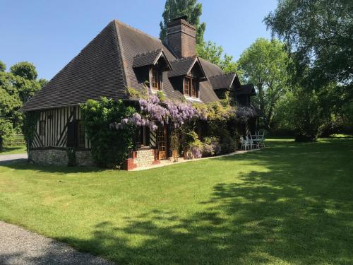 an old house with flowers on the side of it at Maison Normande in Auberville
