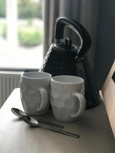 two cups sitting on a table next to a tea kettle at The Courtyard in Bewdley