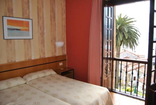 a bedroom with a bed and a large window at Hotel Palacio de los Vallados in Lastres