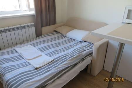 a bed in a room with a desk and a laptop at Smart-House Smart kvartira s kukhnei vozle metro. in Kyiv