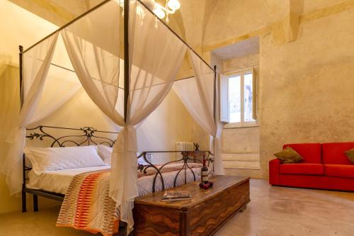 1 dormitorio con cama con dosel y sofá rojo en Palazzo Cariddi, en Nardò