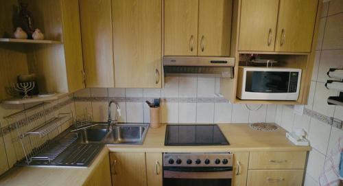 a kitchen with a sink and a stove and a microwave at Coo-ee 9 in Herolds Bay