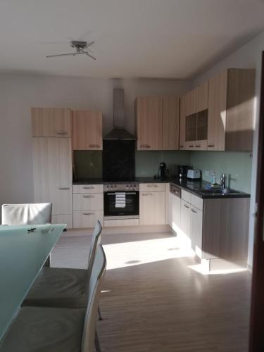 eine Küche mit Holzschränken und einem Tisch im Zimmer in der Unterkunft Modernes 2-Zimmer-Apartment nahe Graz in Gratkorn