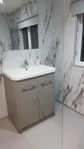 ein weißes Badezimmer mit einem Waschbecken und einem Spiegel in der Unterkunft Ruth's Refresh in Shrewsbury