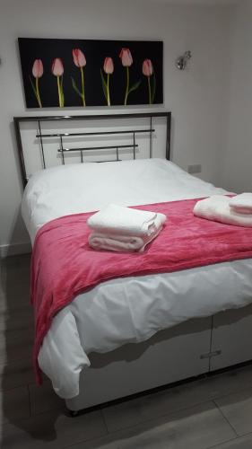 a bed with white towels and pink flowers on the wall at Ruth's Refresh in Shrewsbury