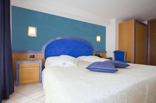 a bedroom with a large bed with a blue headboard at Hotel Ambra in Clusone