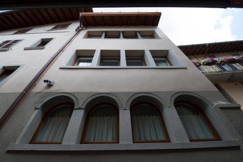 a tall white building with windows and a balcony at Hotel Ambra in Clusone