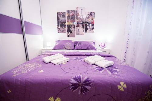 - un lit violet avec 2 serviettes dans l'établissement Apartman Katarina, à Trebinje