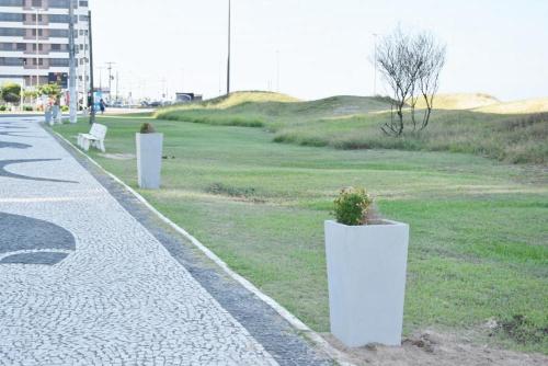a park with three white planters on the grass at Excelente Apartamento Alto Padrão Centro Ed Dubai in Capão da Canoa