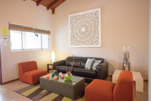 a living room with a leather couch and orange chairs at Costa Esmeralda Village in Palm-Eagle Beach