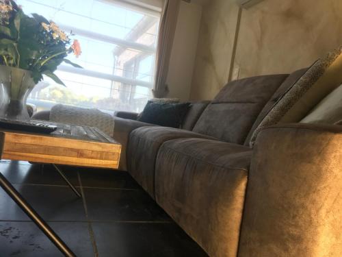 a brown couch sitting in a living room with a table at Het Kleinste Hof in Geraardsbergen