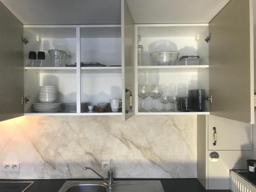 a kitchen with white cabinets with dishes in it at Het Kleinste Hof in Geraardsbergen