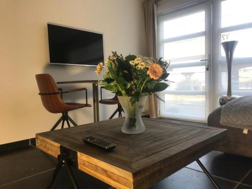 a vase of flowers on a wooden table in a living room at Het Kleinste Hof in Geraardsbergen