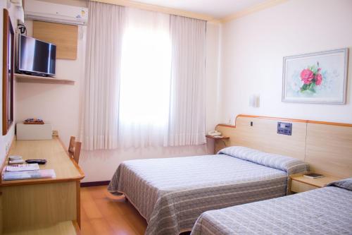 um quarto de hotel com duas camas e uma televisão em Hotel Estação 101 - Brusque em Brusque