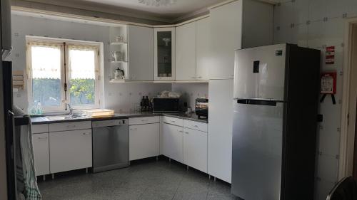 a kitchen with white cabinets and a refrigerator at Villa spacieuse proche de L'océan in Vila Praia de Âncora