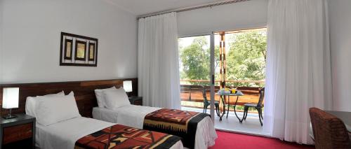 a hotel room with two beds and a balcony at Gran Hotel Tourbillon & Lodge in Puerto Iguazú