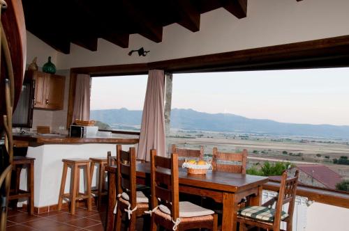 a kitchen with a table and chairs and a large window at Entre las Piedras y musgo in Muñopepe