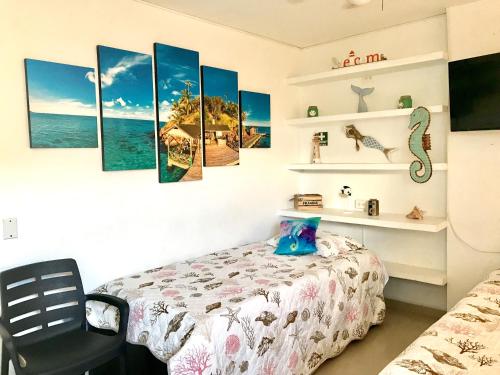 um quarto com uma cama e algumas pinturas na parede em Apto en SAI a metros de la playa - DASH Vacaciones em San Andrés