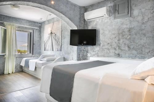 a bedroom with two beds and a flat screen tv at Ilio Maris in Mýkonos City