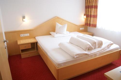 a bedroom with a bed with white sheets and pillows at Falkner Appartement Resort in Längenfeld