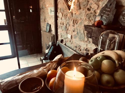 a candle sitting on a table with a bowl of fruit at The Stone Boat Guesthouse for Pilgrims in Rabanal del Camino