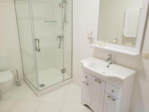 a white bathroom with a shower and a sink at Pride in Tarashcha