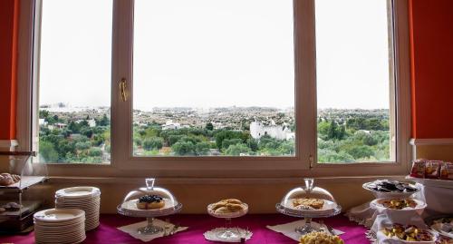 a table with plates of food in front of a window at Semiramide Palace Hotel in Castellana Grotte