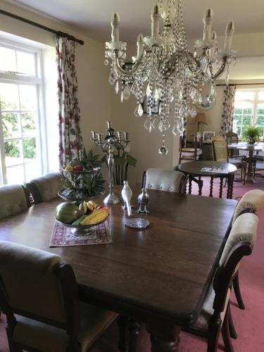 a dining room with a wooden table and a chandelier at High Mead in Woodsford