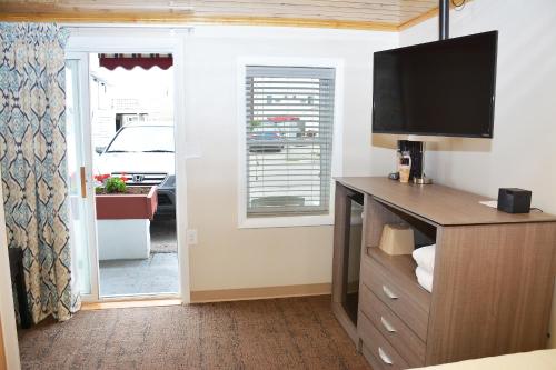 a living room with a tv and a dresser with a television at Alouette Beach Resort Economy Rooms in Old Orchard Beach