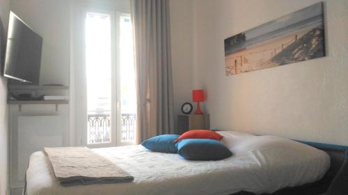 1 dormitorio con cama con almohadas y ventana en Le BLUMARINE, en Cannes