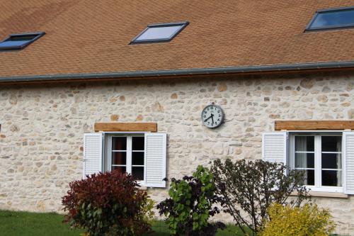 a building with a clock on the side of it at La Bullote - Gîtes - Paris Roissy CDG in Villeneuve-sous-Dammartin