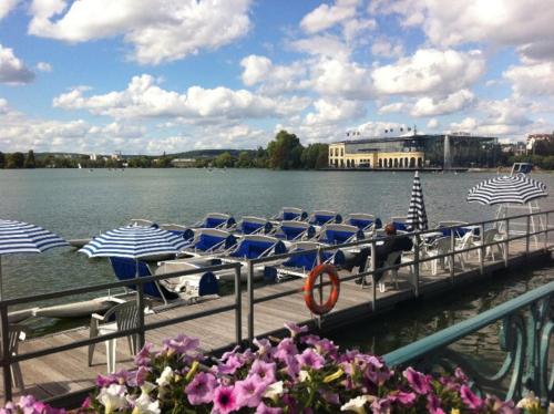 a dock with lounge chairs and umbrellas on the water at une chambre ENGHIEN LES BAINS centre gare in Enghien-les-Bains