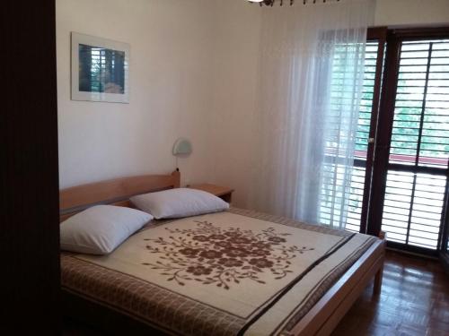 1 dormitorio con 1 cama grande y ventana en Apartments Pere - parking and barbecue, en Povljana
