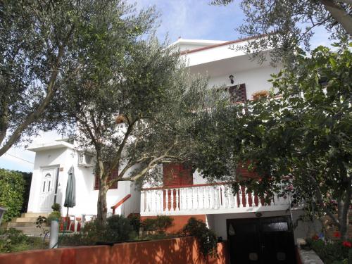 Casa blanca con balcón blanco y árboles en Apartments Pere - parking and barbecue, en Povljana